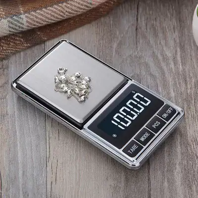 Digital jewelry weight scale displaying silver jewelry on a wooden surface. Ideal for weighing rings, necklaces, and precious metals with precision.