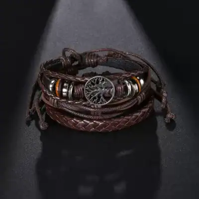 Stylish leather and metal beaded bracelet with a tree of life charm in a fashionable jewelry display. Perfect for accessorizing your look with a blend of natural and edgy elements.