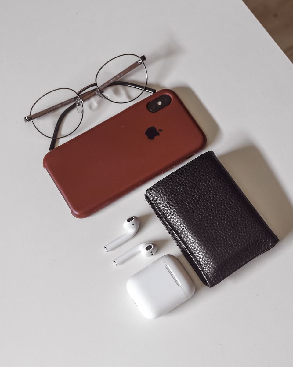 red and black iphone case beside white leather wallet