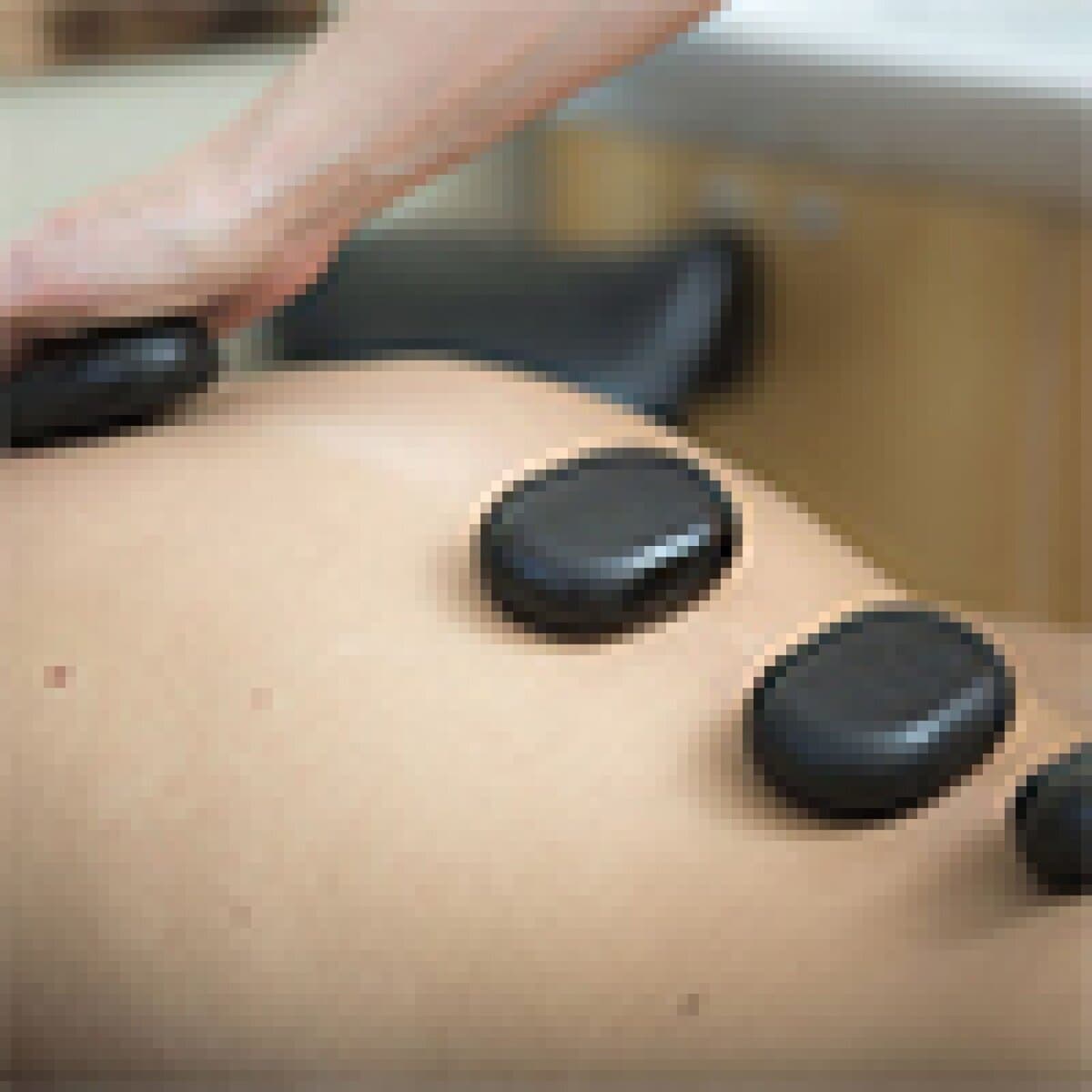 A person receiving hot stone therapy on their back with smooth, heated stones to promote relaxation and stress relief in a serene spa setting.