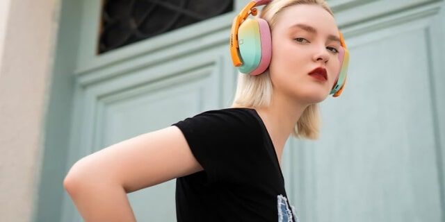 Young woman with colorful headphones and stylish black T-shirt outside.
