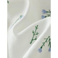 Luxurious white silk scarf with delicate embroidered blue flowers and green foliage, perfect for stylish accessories or gift-giving. Soft, high-quality fabric for comfort and elegance.