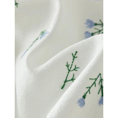 Luxurious white silk scarf with delicate embroidered blue flowers and green foliage, perfect for stylish accessories or gift-giving. Soft, high-quality fabric for comfort and elegance.