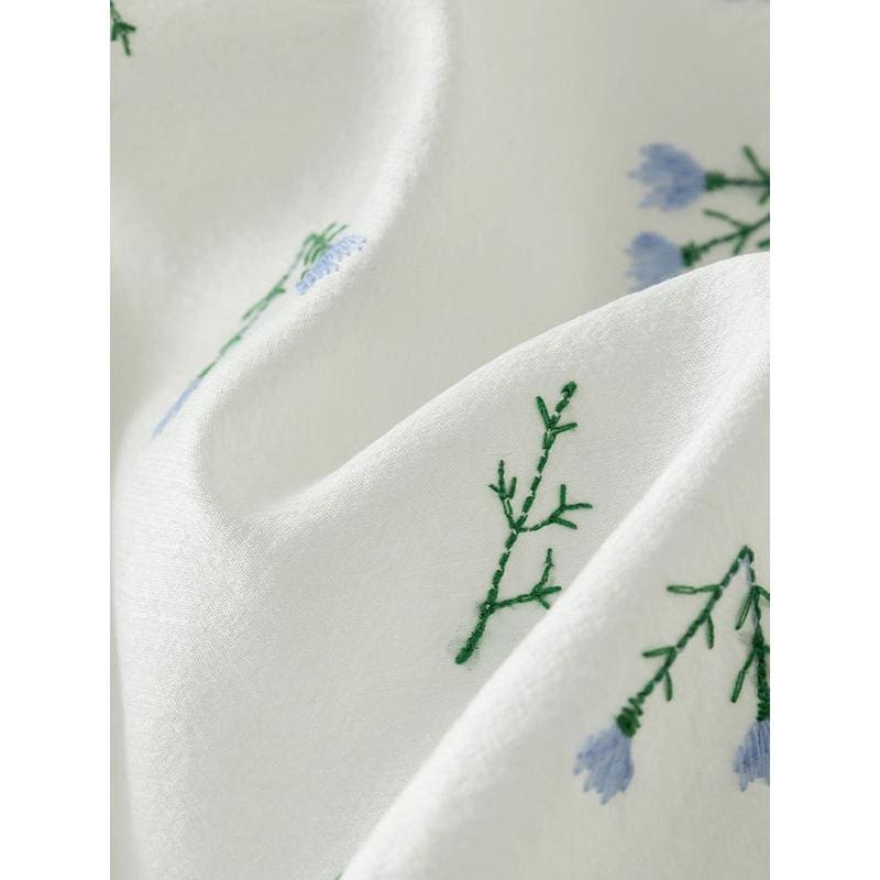 Luxurious white silk scarf with delicate embroidered blue flowers and green foliage, perfect for stylish accessories or gift-giving. Soft, high-quality fabric for comfort and elegance.