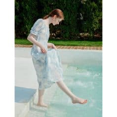 Beautiful woman dipping her toes into a swimming pool, outdoor leisure scene, summertime fashion, relaxed mood, natural light, modern lifestyle image.