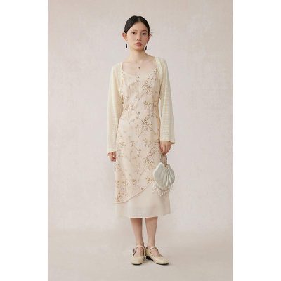 Stylish woman wearing a beige floral lace dress paired with a cozy cream cardigan, holding a trendy white purse, showcasing timeless fashion essentials at Monalisa Store.