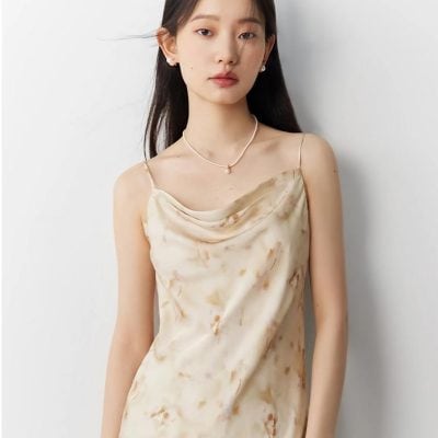 Graceful satin dress featuring soft beige tones, delicate straps, and a stylish cowl neckline, perfect for upscale events and fashionable outings.
