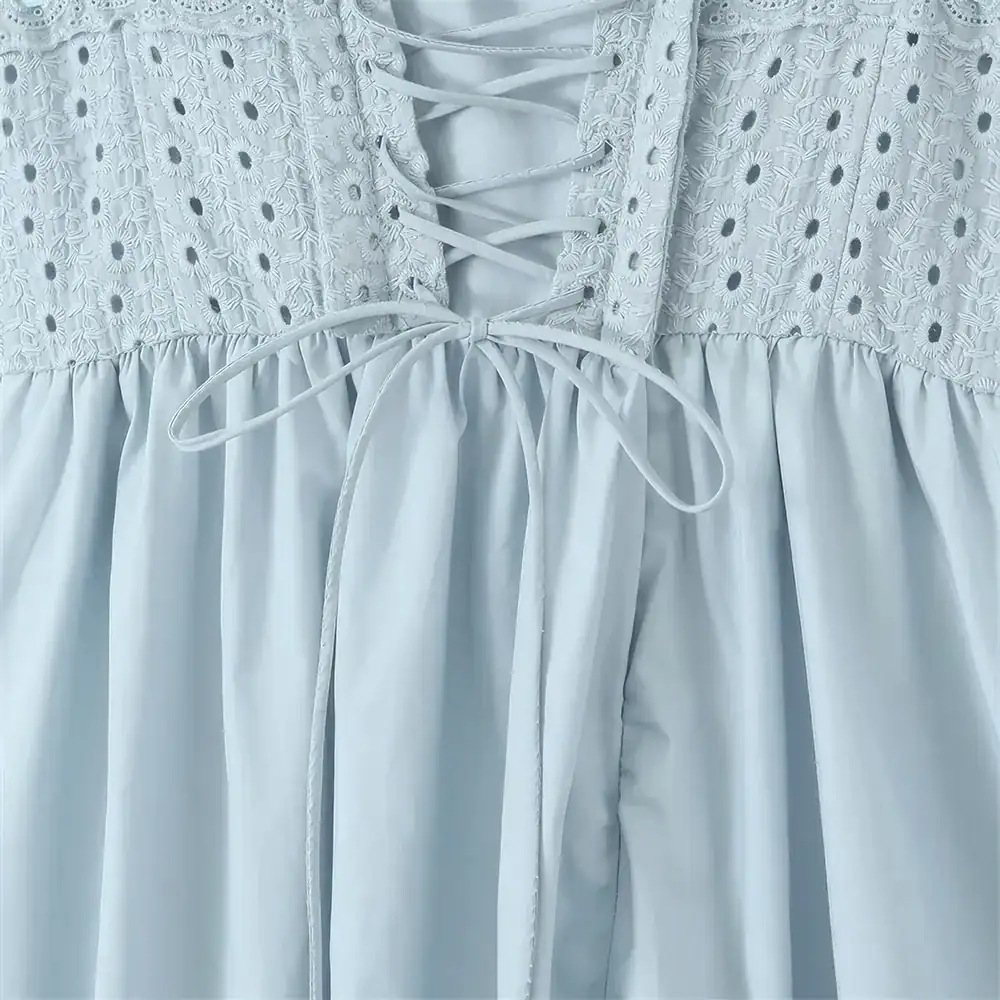 White dress featuring delicate embroidered floral details and a front lace-up tie design, ideal for summer or special occasions.