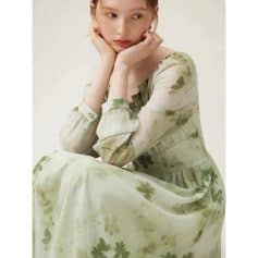 Young woman wearing a delicate, floral-printed dress in muted green tones, perfect for casual or special occasions.