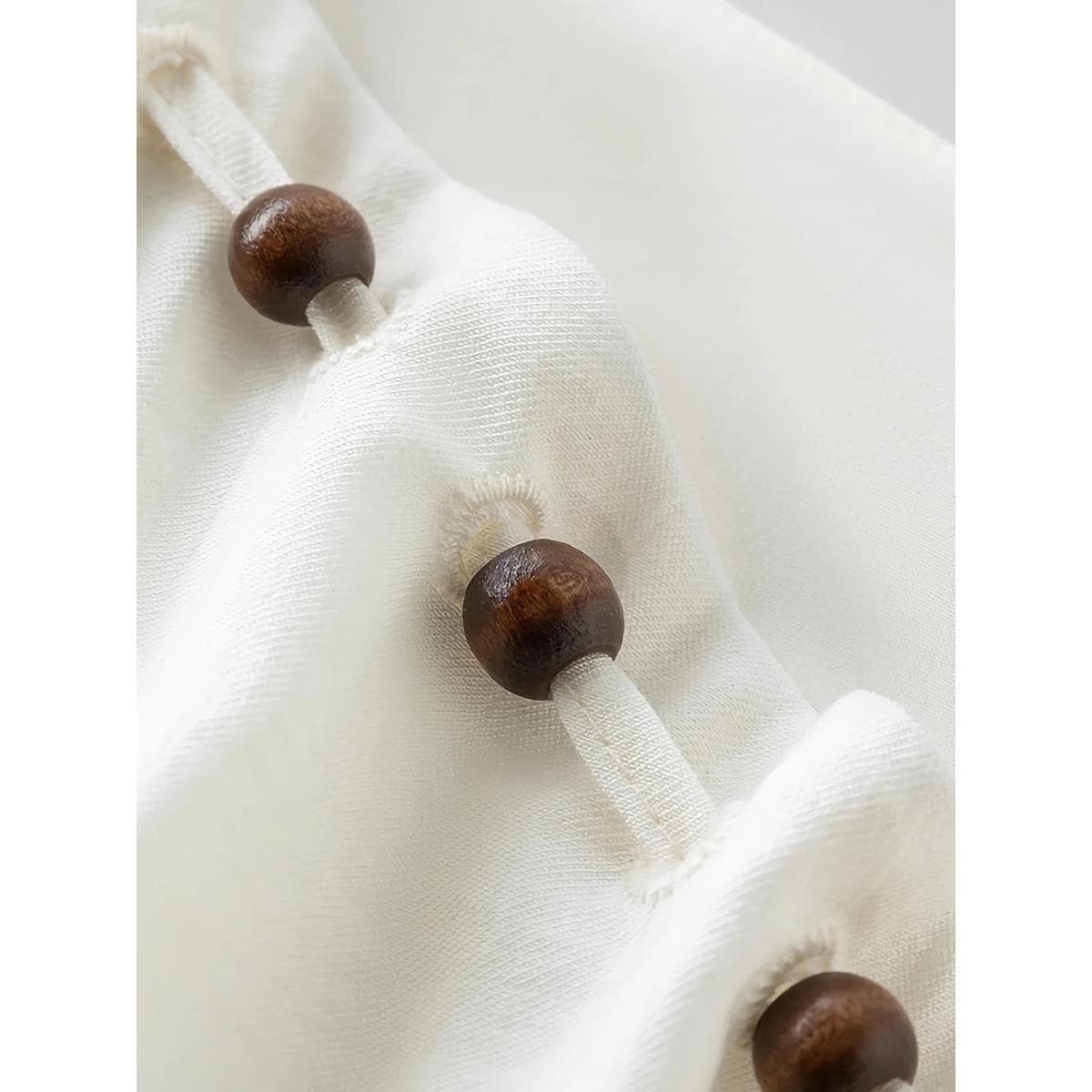 Close-up of a white silk eye mask with dark wooden beads and elastic band, designed for comfort and eye health. Perfect for relaxation, skincare, and luxury eye care from Monalisa Medical.