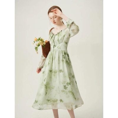 Beautiful woman in a flowy light green floral dress with sheer long sleeves, holding a woven basket with flowers, showcasing stylish and comfortable women's fashion from Monalisa Medical Store.