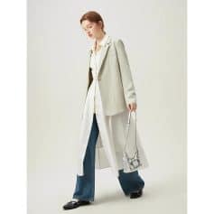 Elegant women's outfit featuring a beige blazer over a long shirt, paired with flared jeans and stylish shoes, showcasing modern fashion and accessories for a sophisticated look.