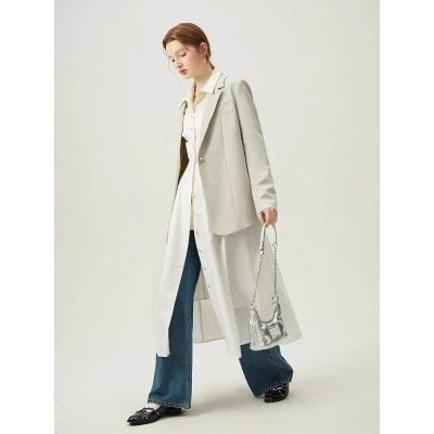 Elegant women's outfit featuring a beige blazer over a long shirt, paired with flared jeans and stylish shoes, showcasing modern fashion and accessories for a sophisticated look.