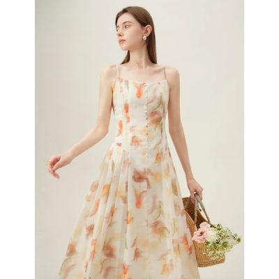 A young woman models a flowy, pastel-colored floral dress with spaghetti straps, highlighting versatile summer fashion options available at Monalisa Store.