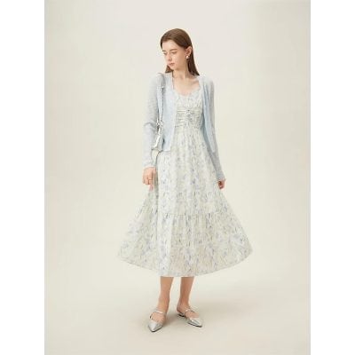 A stylish woman wearing a flowy floral dress paired with a light gray cardigan, perfect for fashionable outings and comfortable wear.