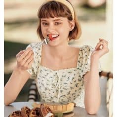 A young woman enjoying a fruit and waffle dessert, showcasing healthy eating options available at Monalisa Store, ideal for eye health supplements and Opt products.
