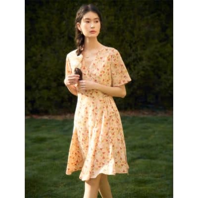 A stylish, light peach floral dress perfect for spring and summer, featuring a V-neck, short sleeves, and flattering A-line silhouette, ideal for casual outings or outdoor events.