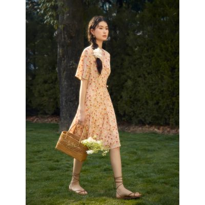 Beautiful woman in floral dress holding basket in garden setting.
