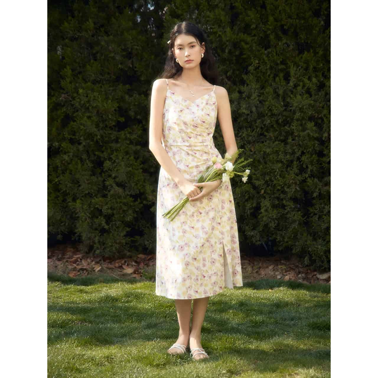 Beautiful woman wearing a floral summer dress outdoors, holding a bouquet of wildflowers, perfect for summer weddings or garden parties.