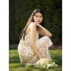 Stunning young woman in floral dress sitting outdoors, showcasing beauty and fashion accessories, perfect for opt and eyewear branding.