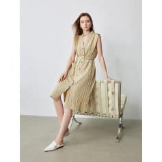 A stylish sleeveless beige midi dress with a button-down front, pleated details, and a waist tie, perfect for casual or semi-formal occasions.
