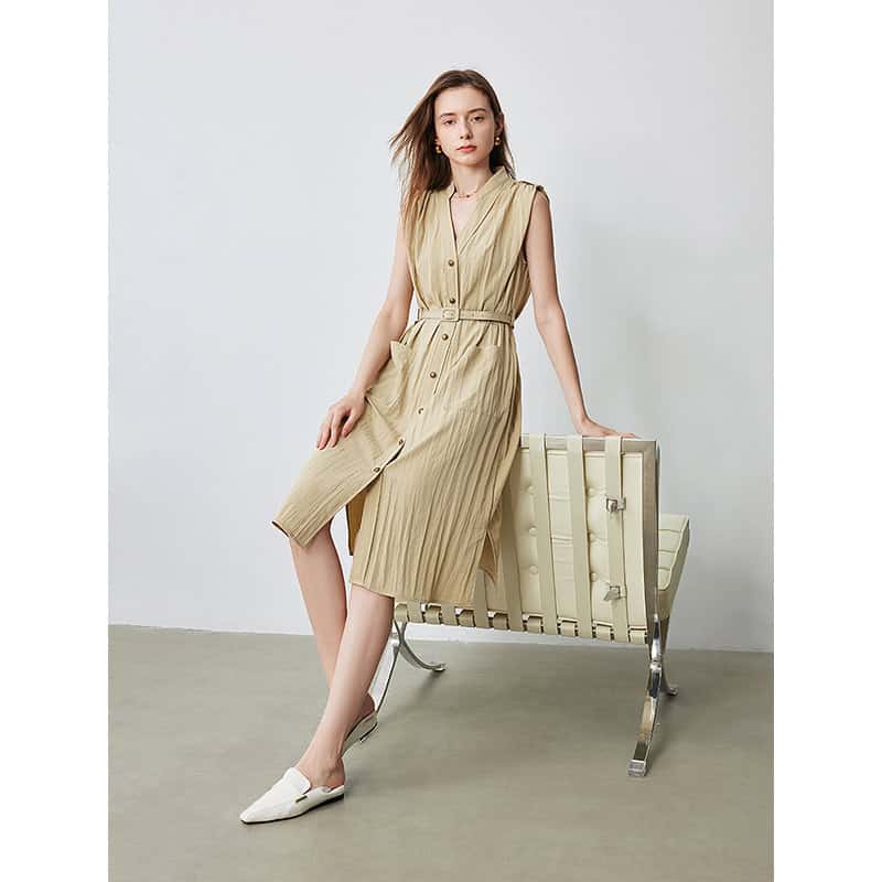 A stylish sleeveless beige midi dress with a button-down front, pleated details, and a waist tie, perfect for casual or semi-formal occasions.