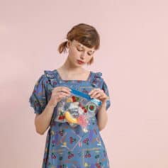 Young woman holding a bag of colorful sweets, playful and vibrant, showcasing trendy fashion and fun accessories for a youthful, cheerful look.