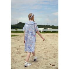Child girl wearing a playful, patterned dress with matching headband outdoors, showcasing stylish kids' fashion and comfortable summer apparel for children.