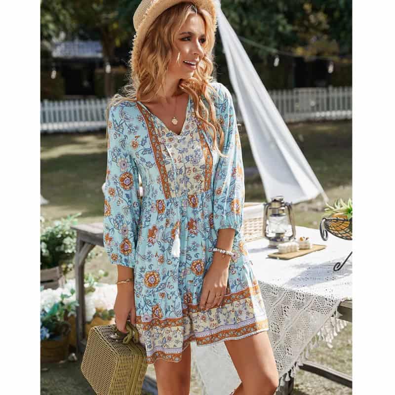 A woman wearing a stylish, floral boho summer dress in an outdoor garden setting. Perfect for casual, beach, or picnic occasions, showcasing trendy summer fashion.