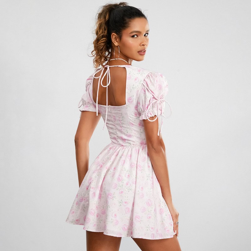 Stylish pink floral summer dress with puff sleeves and tie-back detail, perfect for casual or special occasions.