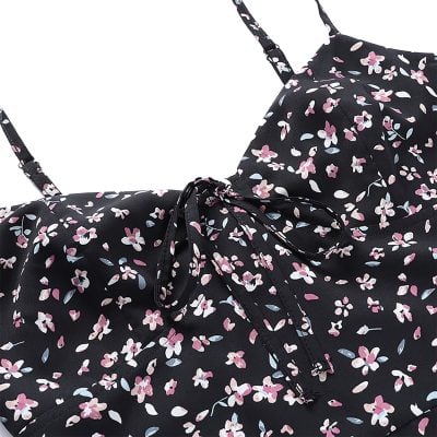 Brightly colored floral dress featuring a black background and pink, white, and blue flower print. Includes adjustable spaghetti straps and a tied bow at the waist for a flattering fit. Ideal for spring or summer fashion.