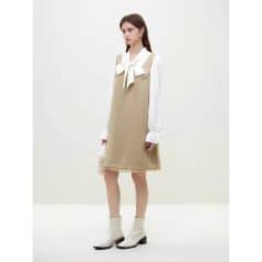 A fashionable model showcases a beige dress layered over a white blouse with a bow tie, complemented by white ankle boots. The outfit exudes elegance and modern style, emphasizing comfort and sophistication. Perfect for fashion-forward women looking for versatile, trendy apparel available at Monalisa Store.