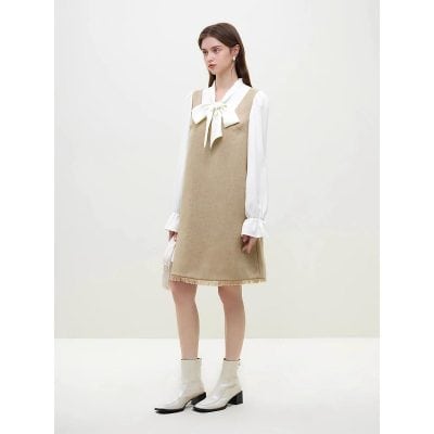 A fashionable model showcases a beige dress layered over a white blouse with a bow tie, complemented by white ankle boots. The outfit exudes elegance and modern style, emphasizing comfort and sophistication. Perfect for fashion-forward women looking for versatile, trendy apparel available at Monalisa Store.