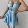 Stylish light blue halter dress with deep V-neck, ruched waist, and flowing skirt, perfect for summer outings and casual occasions.