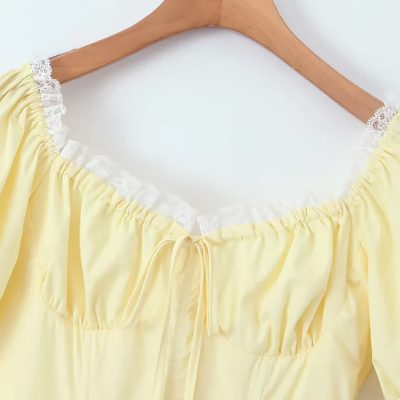 Soft yellow lingerie top with delicate lace trim on the neckline, adjustable drawstring, and ruffled elastic shoulders. Perfect for sleepwear or intimate wear.