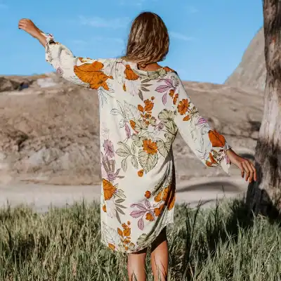 A woman wearing a floral dress enjoying outdoors, showcasing vibrant summer fashion ideal for women’s casual and resort wear, perfect for outdoor activities and stylish summer occasions.