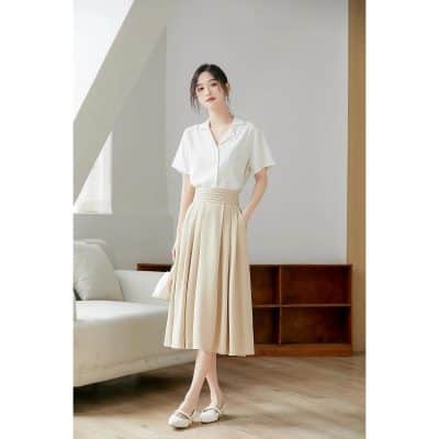 Stylish woman wearing sophisticated white blouse and beige pleated skirt in modern opt shop setting. Perfect for professional or casual eyewear shopping.