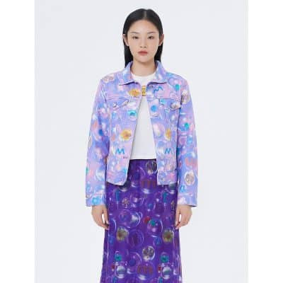 A woman wearing a colorful, bubble-patterned denim jacket and matching skirt designed for stylish optical eyewear fashion. Perfect for modern, trendy eyewear enthusiasts.