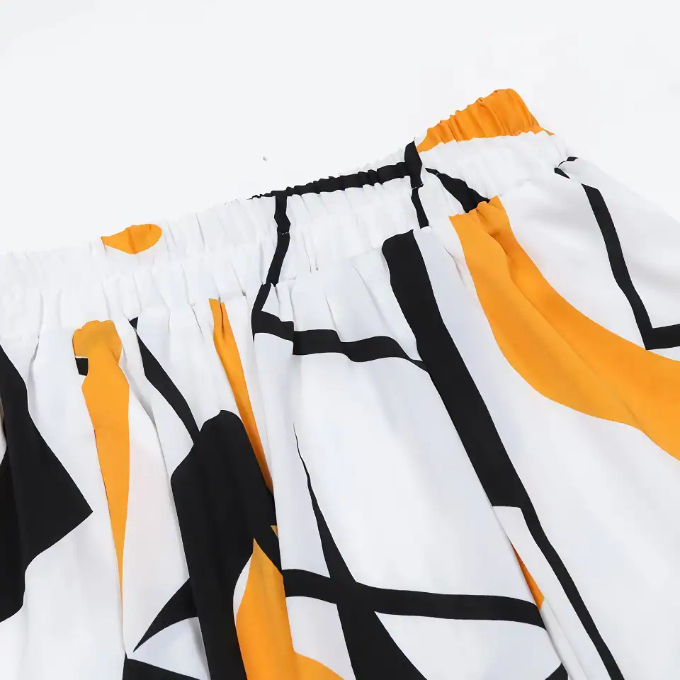 Colorful shorts with bold black, white, and orange geometric patterns, featuring an elastic waistband, perfect for casual wear and summer fashion statements.