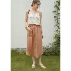 Young woman wearing a floral top and tan satin skirt in a garden setting, showcasing trendy women's fashion for casual and everyday wear.
