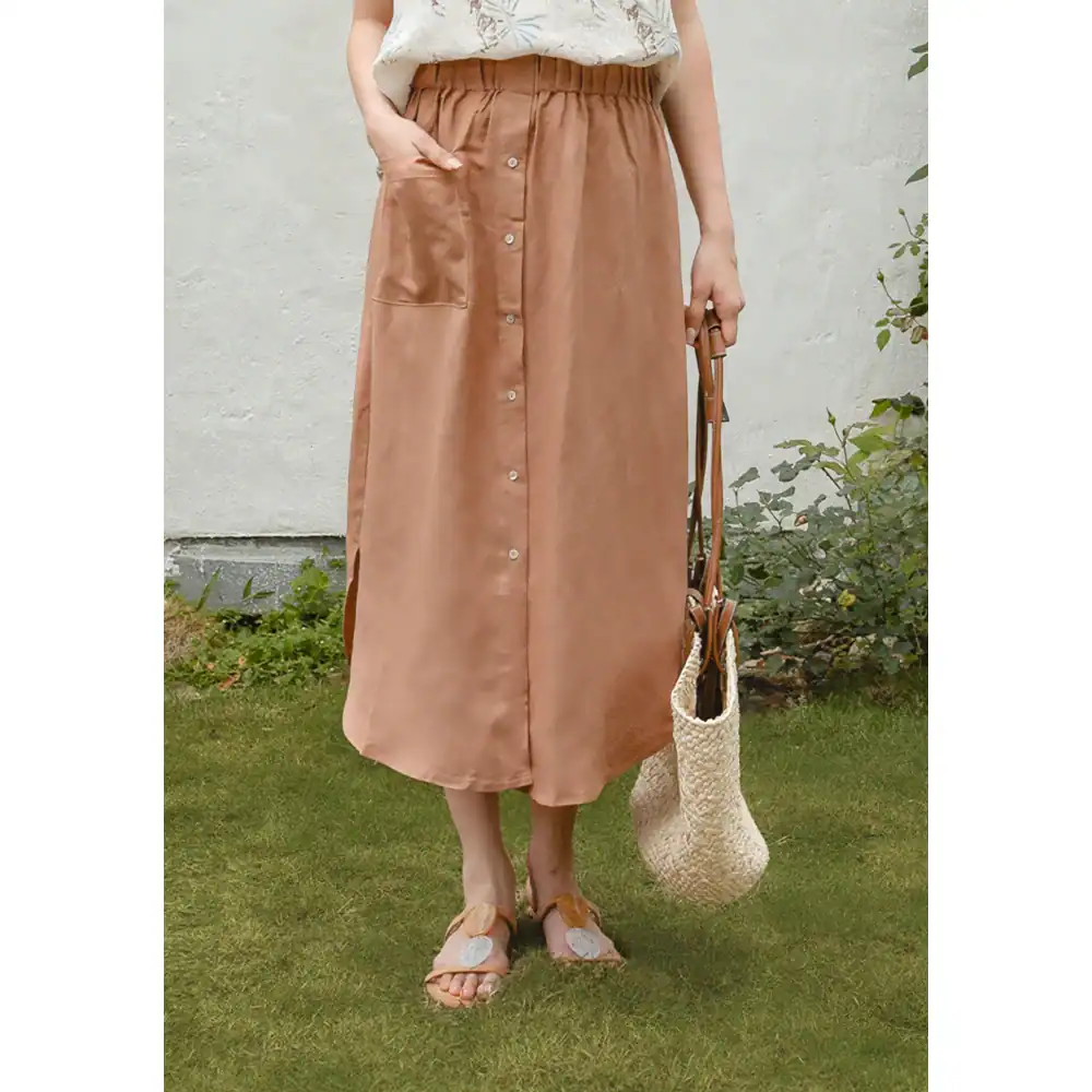 Elegant long beige satin skirt with button details, flowy design, and comfortable fit for women. Perfect for casual or dressy occasions.