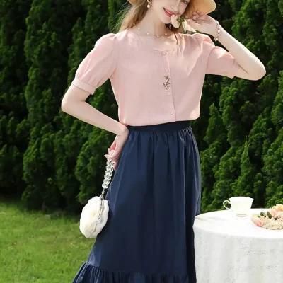 Stylish woman in pink top and navy skirt, accessorized with a wide-brim hat and floral handbag, showcasing fashionable summer outfits available at Monalisa Store.