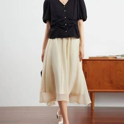 Fashionable women's black top paired with a cream flowy skirt, ideal for stylish occasions and sophisticated look.