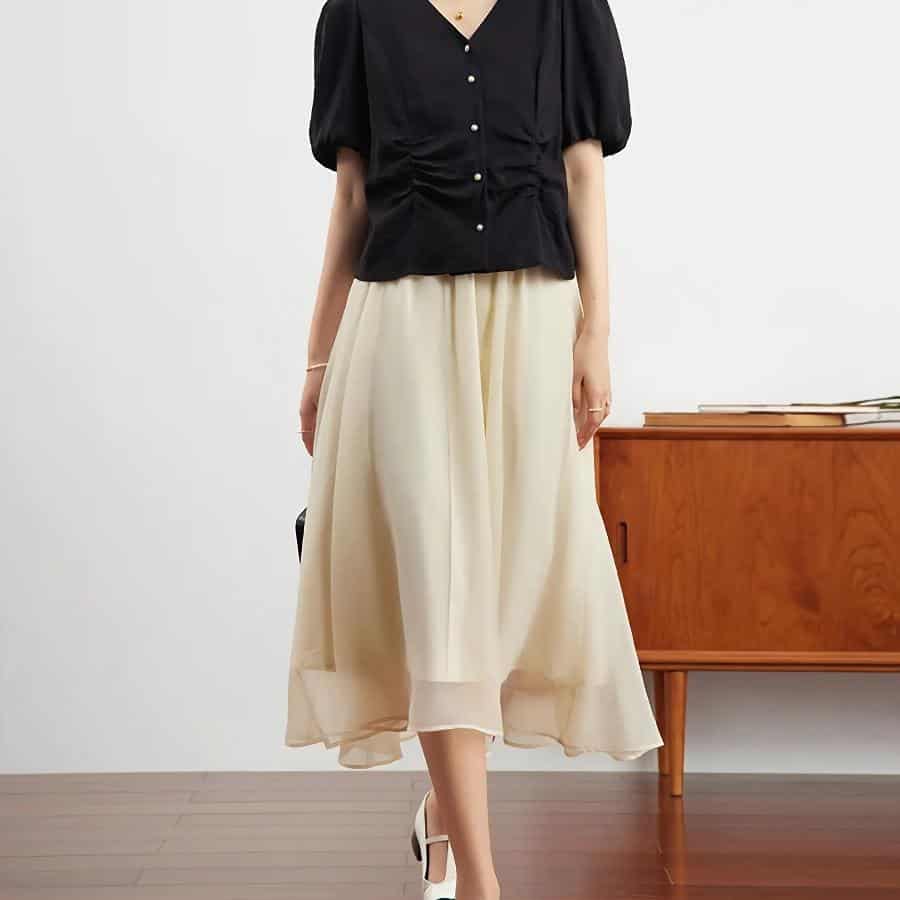 Fashionable women's black top paired with a cream flowy skirt, ideal for stylish occasions and sophisticated look.