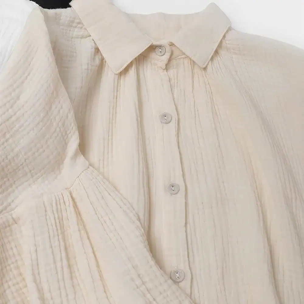 Cream-colored blouse with textured fabric and button-up design, perfect for stylish office wear or casual outings.