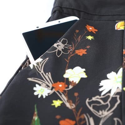 Close-up of a black fabric with colorful floral print holding a smartphone in a pocket, perfect for fashion-forward accessories and convenient storage while on the go.