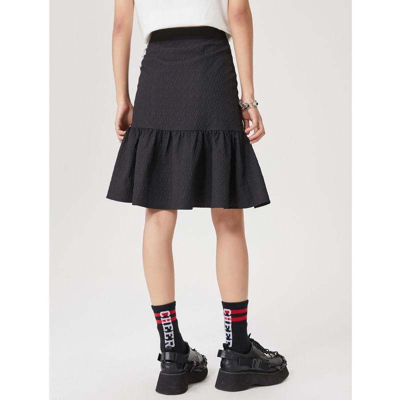 A stylish black skirt with textured fabric and ruffled hem, perfect for fashionable women looking for trendy and comfortable clothing options.