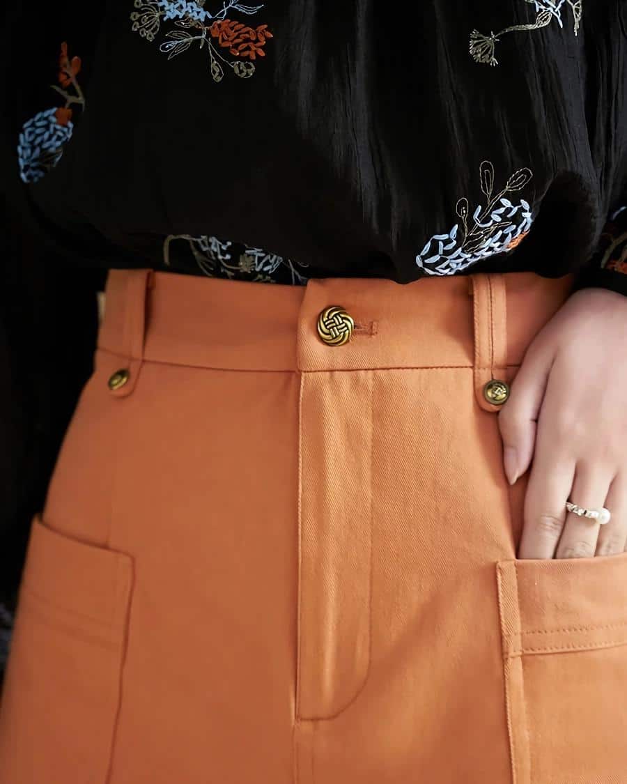 Stylish orange skirt with gold buttons, featuring a high waist design and large front pocket, ideal for professional or casual wear, available at Monalisa Store.