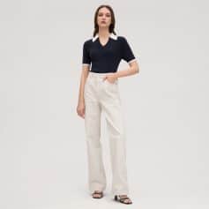 Alt text: Stylish woman wearing navy sweater with white collar and beige wide-leg jeans, showcasing trendy casual fashion.