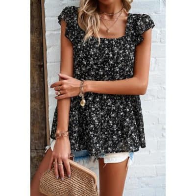 Close-up of a fashionable women’s black floral top, paired with jewelry, denim shorts, and a woven purse, perfect for summer fashion and casual outings.